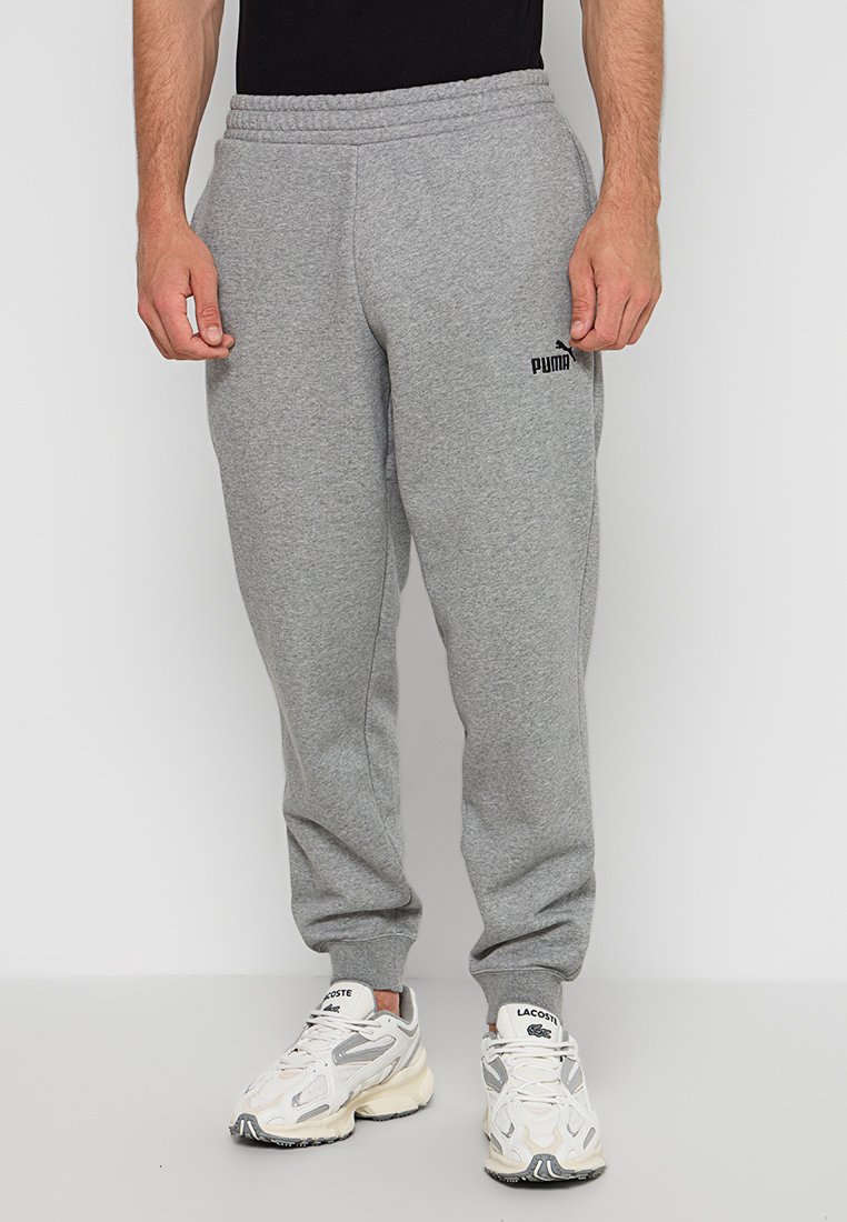 Pantalon de survêtement en coton gris avec une taille élastique, présentant un petit logo Puma noir sur la cuisse gauche, conçu pour le confort et la flexibilité.