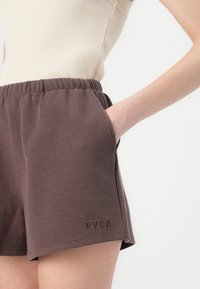 Brune shorts med vaffelmønster og elastisk liv, med sidelommer og en liten RVCA-logo på kanten.