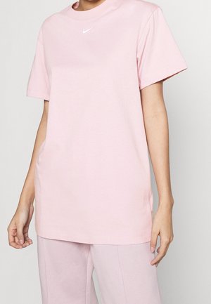 T-shirt en coton rose avec un col rond, des manches courtes et un petit logo Nike blanc sur la poitrine, présentant une coupe décontractée et des fentes sur les côtés.