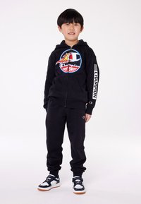 Set di felpa nera con cappuccio e pantaloni della tuta, con logo floreale sul petto, polsini elasticizzati e lettering bianco "Champion" sulle maniche.