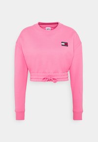 Felpa rosa corta con maniche lunghe, scollo rotondo e orlo con cordino. Presenta un piccolo logo ricamato sulla zona sinistra del petto. Tessuto morbido.