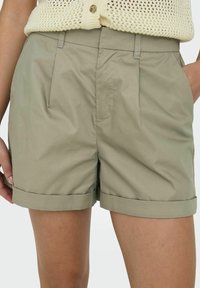 Khaki shorts dengan desain yang disesuaikan, dilengkapi dengan lipatan depan, saku samping, dan bentuk cuff yang digulung, terbuat dari kain ringan.