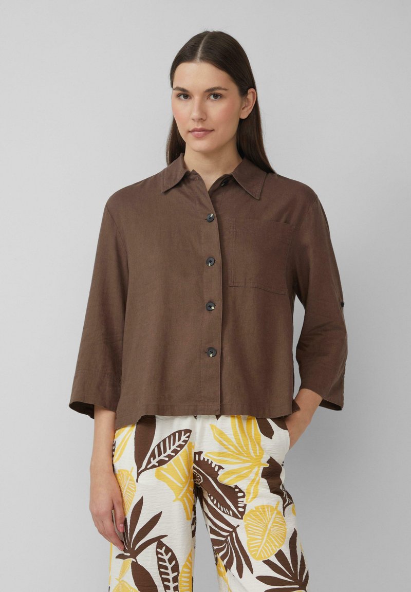 Bruine linnen blouse met kraag, knopen aan de voorkant en een borstzak. Driekwartmouwen zorgen voor een ontspannen pasvorm.