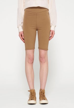 Bordeaux fietsenbroek gemaakt van rekbare stof, met een hoge tailleband en gestikte zoom, gecombineerd met beige hoge sneakers.