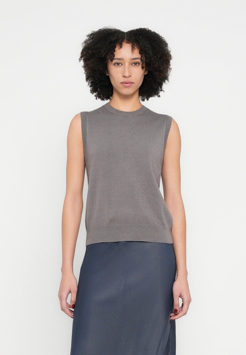 Top gri fără mâneci, strâmt, din tricot cu gât rotund și tiv nervurat. Purtați cu o fustă netedă bleumarin închis.