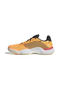 Chaussure de sport basse orange vif avec lacets noirs, semelle blanche, accent rouge au talon et panneaux latéraux en mesh pour la ventilation.