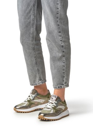 Sneakers verdi e metallizzate con motivi testurizzati, dettagli bianchi e suole in gomma. Indossate con jeans grigi chiari tagliati sopra la caviglia.