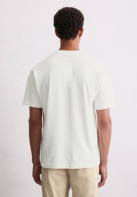 Helle beige Kurzarm-T-Shirt mit Rundhalsausschnitt, glatter Textur, minimalistischem Design und ohne sichtbare Logos oder Muster.