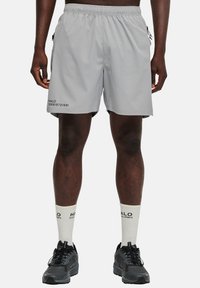 Grå idrottsshorts med elastisk midja, sidofickor och svarta textdetaljer. Matchas med vita strumpor och svarta idrottsskor.