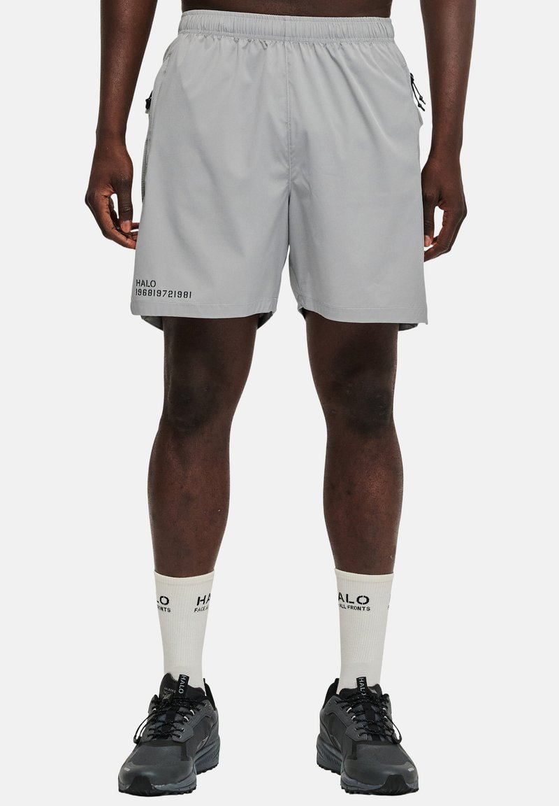 Grå idrottsshorts med elastisk midja, sidofickor och svarta textdetaljer. Matchas med vita strumpor och svarta idrottsskor.