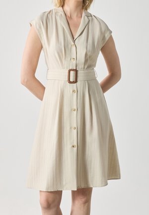Beige jurk met korte mouwen met verticale strepen, knopen aan de voorkant, een kraag en een bijpassende riem met een bruine rechthoekige gesp.