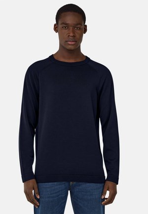 Sweatshirt à manches longues bleu marine en tissu doux. Doté d'un col rond côtelé, de manches raglan et d'un ourlet droit. Porté avec un jean.