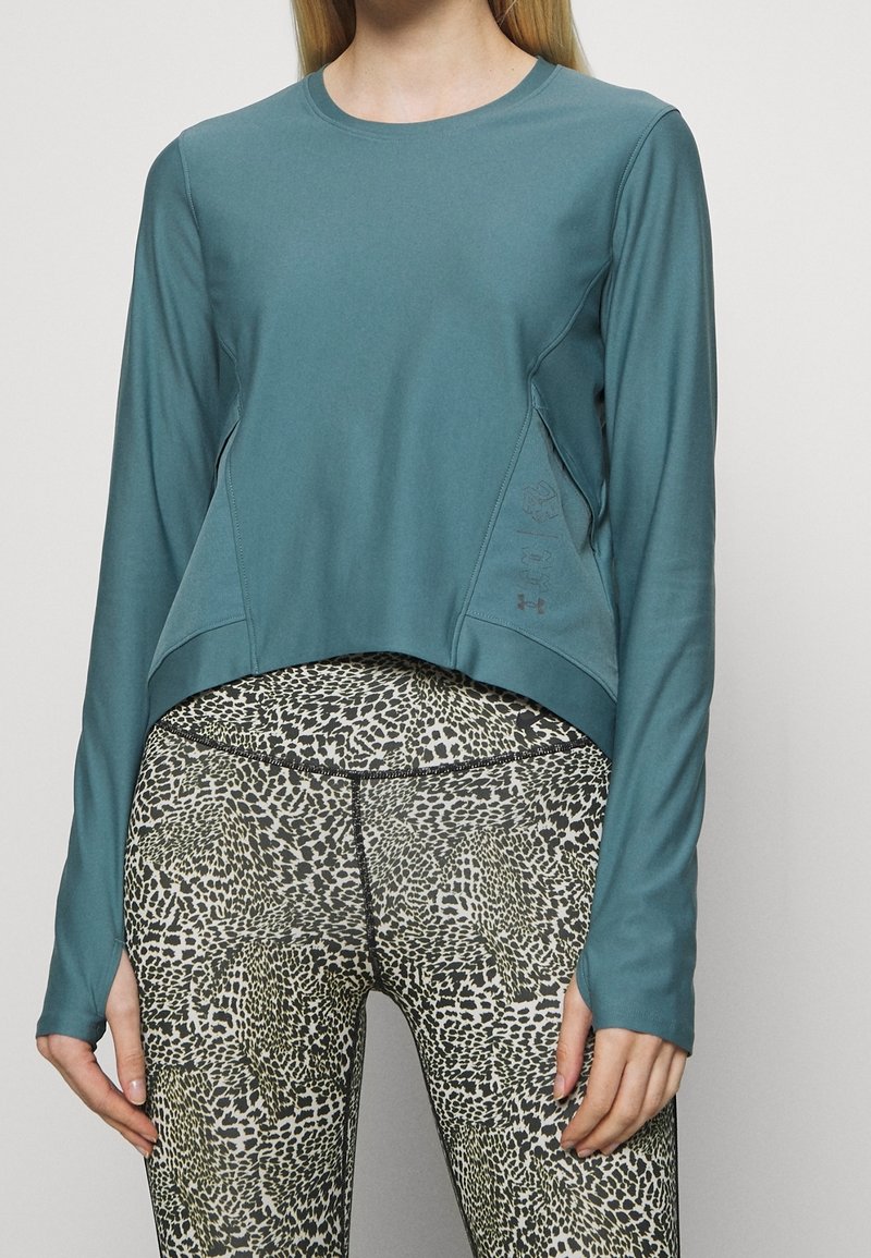 Türkises Langarmshirt mit cropped Design und Seitenpaneelen, kombiniert mit enganliegenden Leggings im Leopardenmuster.