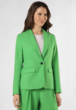Grüner maßgeschneiderter Blazer mit einem einzelnen schwarzen Knopf, Reverskragen und zwei Vordertaschen, kombiniert mit passenden Hosen. Glatte Textur.