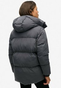 Grå puffjakke med hætte, med en quiltet design og en let blank overflade. Slutter ved hofte længde med et afslappet fit.