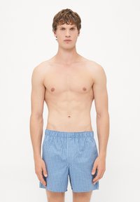 Pantaloni da bagno a quadri azzurri con vita elasticizzata, realizzati in un tessuto leggero e dalla vestibilità ampia, adatti per la spiaggia o la piscina.