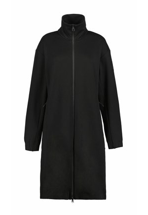 Abrigo largo negro con cuello alto y cremallera frontal completa, con mangas largas y dos bolsillos laterales.