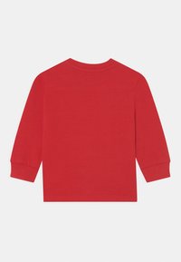 En enfärgad röd långärmad tröja för småbarn med ribbade manschetter och rundad halsringning, visad platt bakifrån på en vit bakgrund.