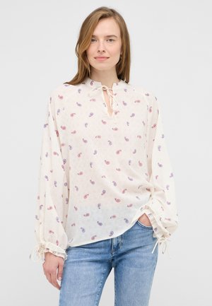 Blouse blanche avec un imprimé paisley rouge et bleu. Tissu léger, manches longues avec des liens aux poignets et un col fendu.