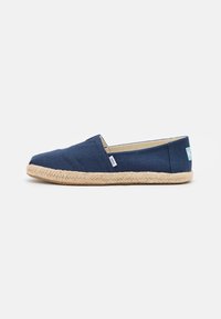 Marineblauwe canvas espadrille met een gevlochten jute zool, voorzien van een instapontwerp en een minimalistisch merkteken aan de zijkant.