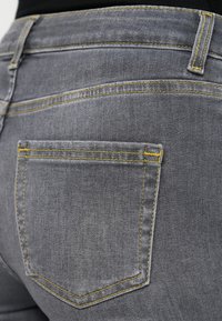 Γκρι τζιν παντελόνι από τζιν με κίτρινη ραφή, πίσω τσέπη σε ορθογώνιο σχήμα και λείο, υφασμάτινο ύφασμα με υφή.