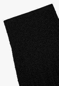 Schwarzer, strukturierter Schal mit einer weichen, zerknitterten Oberfläche, rechteckiger Form, der unregelmäßige Muster aufweist. Leichtes und flexibles Material.