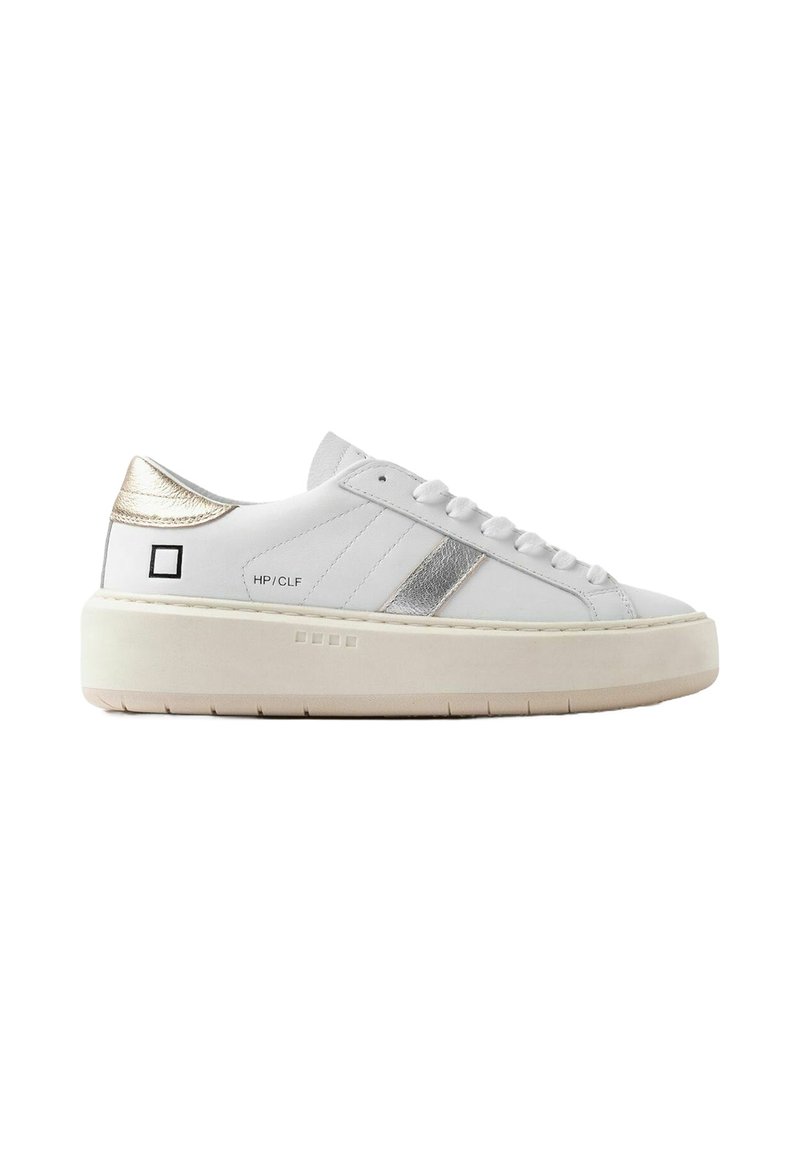 Zapatilla de cuero blanca con acentos plateados, suela plana de goma natural, talón texturizado y un diseño de línea cosida en el costado.