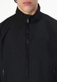 Black jacket featuring a high collar, full-length front zipper, and two side zipper pockets with a smooth texture.