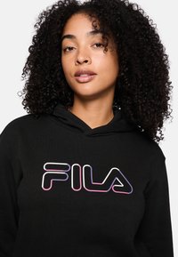 Felpa nera con cappuccio realizzata in tessuto morbido, con un design del logo FILA colorato in bianco, rosa e viola. Cappuccio regolabile con coulisse.