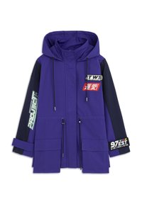 Lila und marineblaue Outdoor-Jacke mit Kapuze, Kordeln, mehreren Taschen und verschiedenen farbigen Aufnähern mit Text und Grafiken.