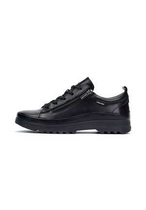 Black leather sneaker with a rounded toe, lace-up front, and side zipper. Textured sole with deep grooves for traction.