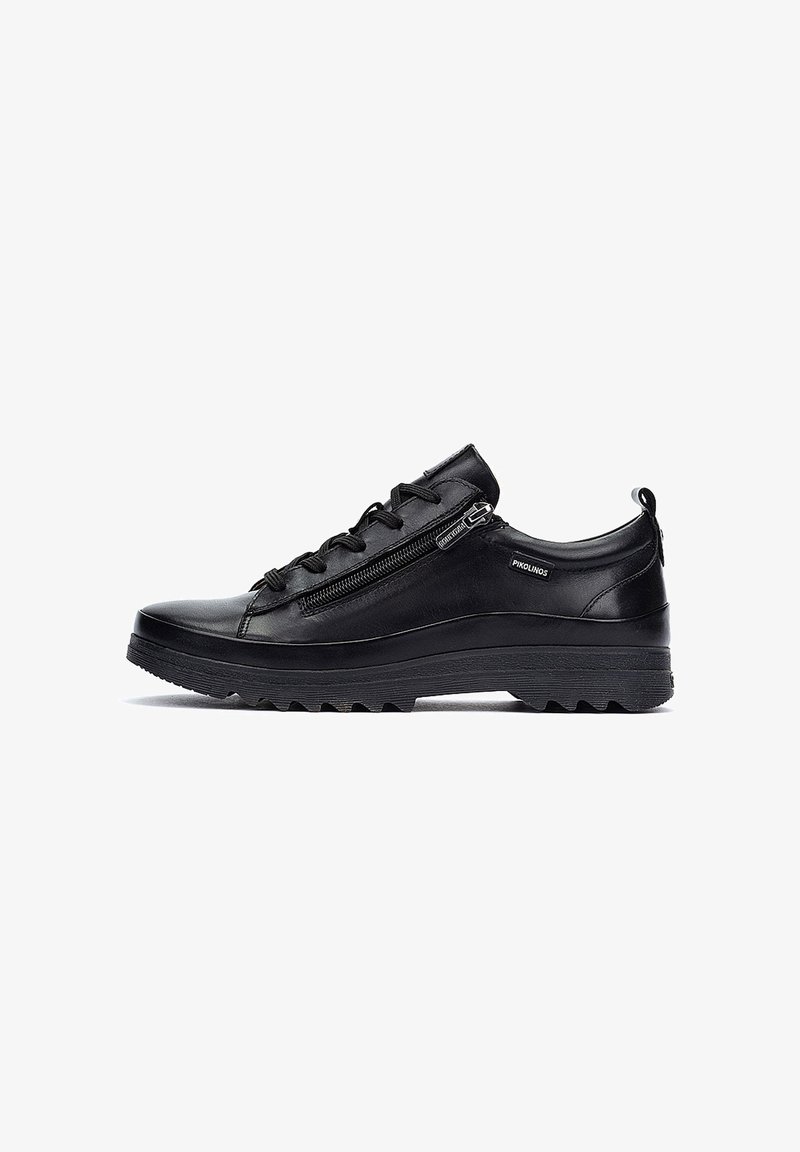 Black leather sneaker with a rounded toe, lace-up front, and side zipper. Textured sole with deep grooves for traction.