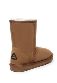 Braune Wildleder-Stiefelette mit einem weichen, weißen Fellfutter, runder Zehenform und flacher Gummisohle. Mit kleinem Logo des Herstellers an der Seite.