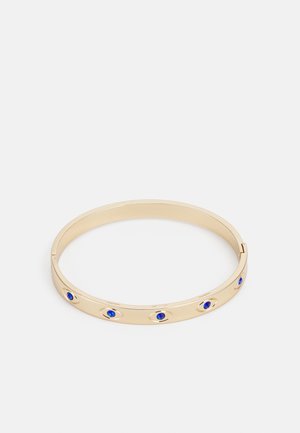 Guld armbånd med fem jævnt fordelte blå ædelstens øje-formede designs på en hvid baggrund.