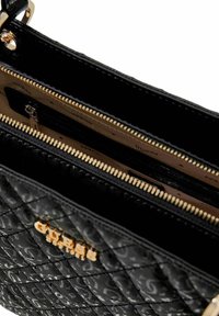 Borsa nera trapuntata con dettagli in oro, dotata di chiusura a zip e molteplici tasche interne. Nome del marchio impresso all'esterno.