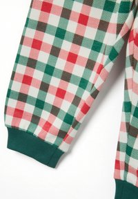 Mouw van stof met een rood, groen en wit geblokt patroon en een groene geribbelde manchet op een lichte achtergrond.