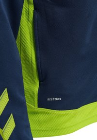 Marinblå träningströja med limegröna detaljer. Texturerat tyg med en meshpanel och sidoficka. "BEECOOL"-logotyp på den nedre fållen.