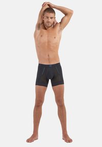 Schwarze Boxershorts mit blauen Akzenten und Mesh-Details. Enganliegendes Design, dehnbarem Material und elastischem Bund. Modell steht.