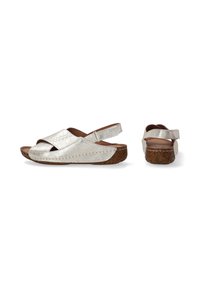 Sandales argentées métalliques à talon ouvert avec des brides croisées, semelle en liège et coutures texturées le long du bord. Sangle réglable en Velcro au niveau du talon.
