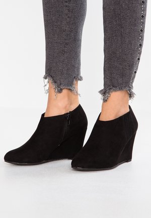 Black suede wedge ankle boots with a side zipper, smooth texture, rounded toe, and elastic side panels for a snug fit.