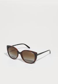 Ochelari de soare cu model țestoasă, cu o formă largă în stil cat-eye, lentile de culoare maro cu degradé și brațe negre cu branding alb "VOGUE".