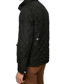 Giacca nera trapuntata con colletto alto, tasche laterali e dettagli in bottone a pressione. Presenta un esterno testurizzato e una vestibilità sagomata.