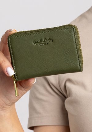 Groene leren portemonnee met een ritsluiting, gekenmerkt door reliëfbranding en een gouden rits, vastgehouden in een hand tegen een neutrale achtergrond.