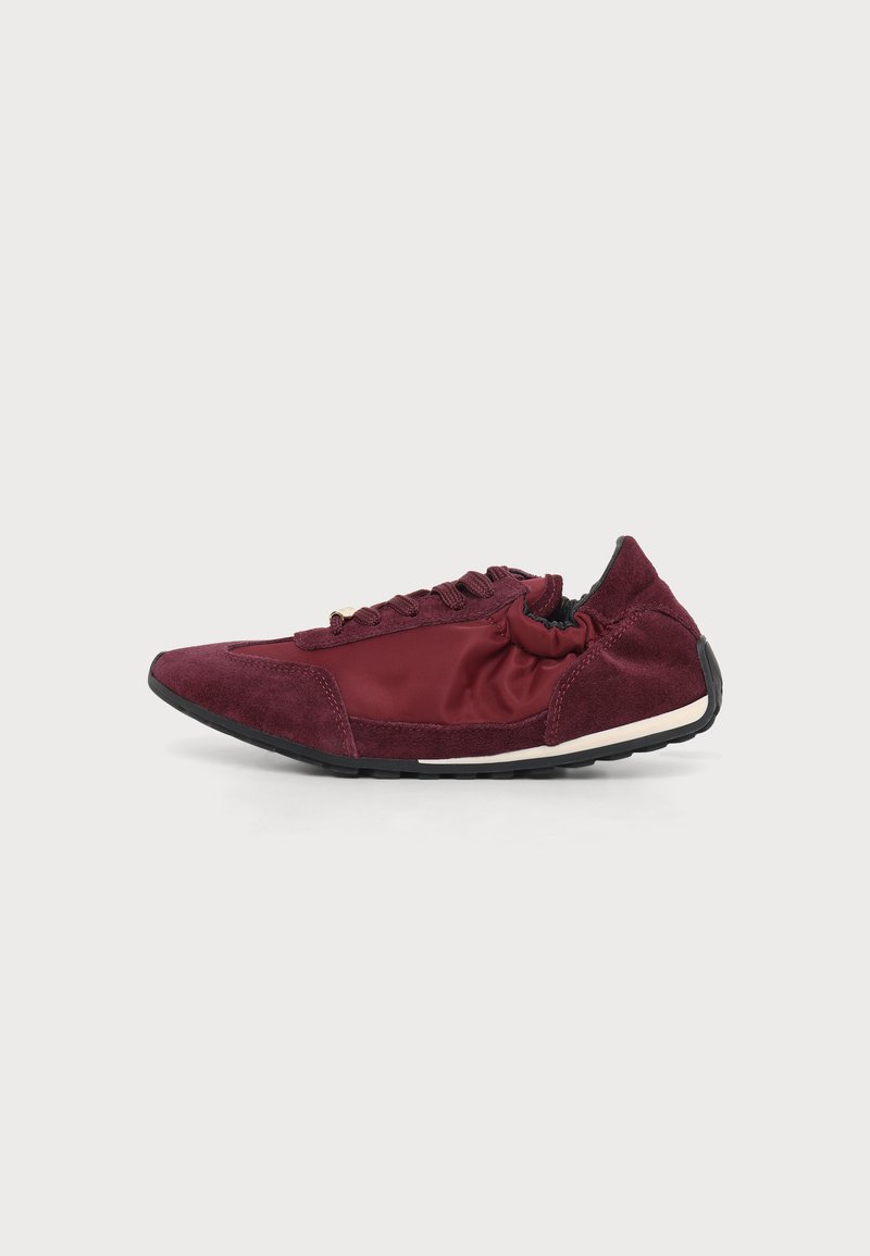 Baskets bordeaux profil bas avec lacets à l’avant, dessus en suède et nylon, col élastique et semelle extérieure en caoutchouc noir sur fond clair uni.