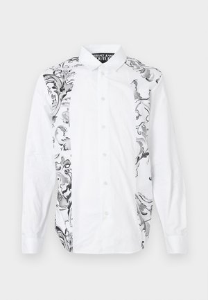 Bela srajca s gumbi, ki na eni strani vsebuje zapletene črno-sive cvetlične vzorce, izdelana iz gladkega materiala z dolgimi rokavi.