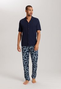Camicetta a maniche corte blu navale con bottoni e pantaloni a fantasia floreale blu navy e azzurri, con una vestibilità ampia e una texture morbida.