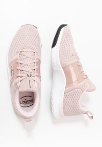 Ljusrosa träningsskor med en ventilationsvänlig mesh-överdela, texturerade detaljer, transparenta inslag och en vit sula med svart grepp.