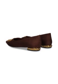 Bailarinas de ante marrón con puntera redonda, detalles dorados en la parte delantera y un tacón decorativo con tachuelas doradas. Textura suave, diseño minimalista.