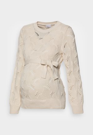 Gräddfärgad graviditetströja med ett texturerat stickat mönster med blommor, ett knytbälte i midjan och ribbstickade ärmslut.