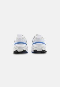 Weiße Sportlich Schuhe mit blauen Akzenten, ausgestattet mit einem strukturierten Obermaterial, dicker Sohle und verstärktem Fersenbereich. Schwarze Außensohle mit Grip-Details.